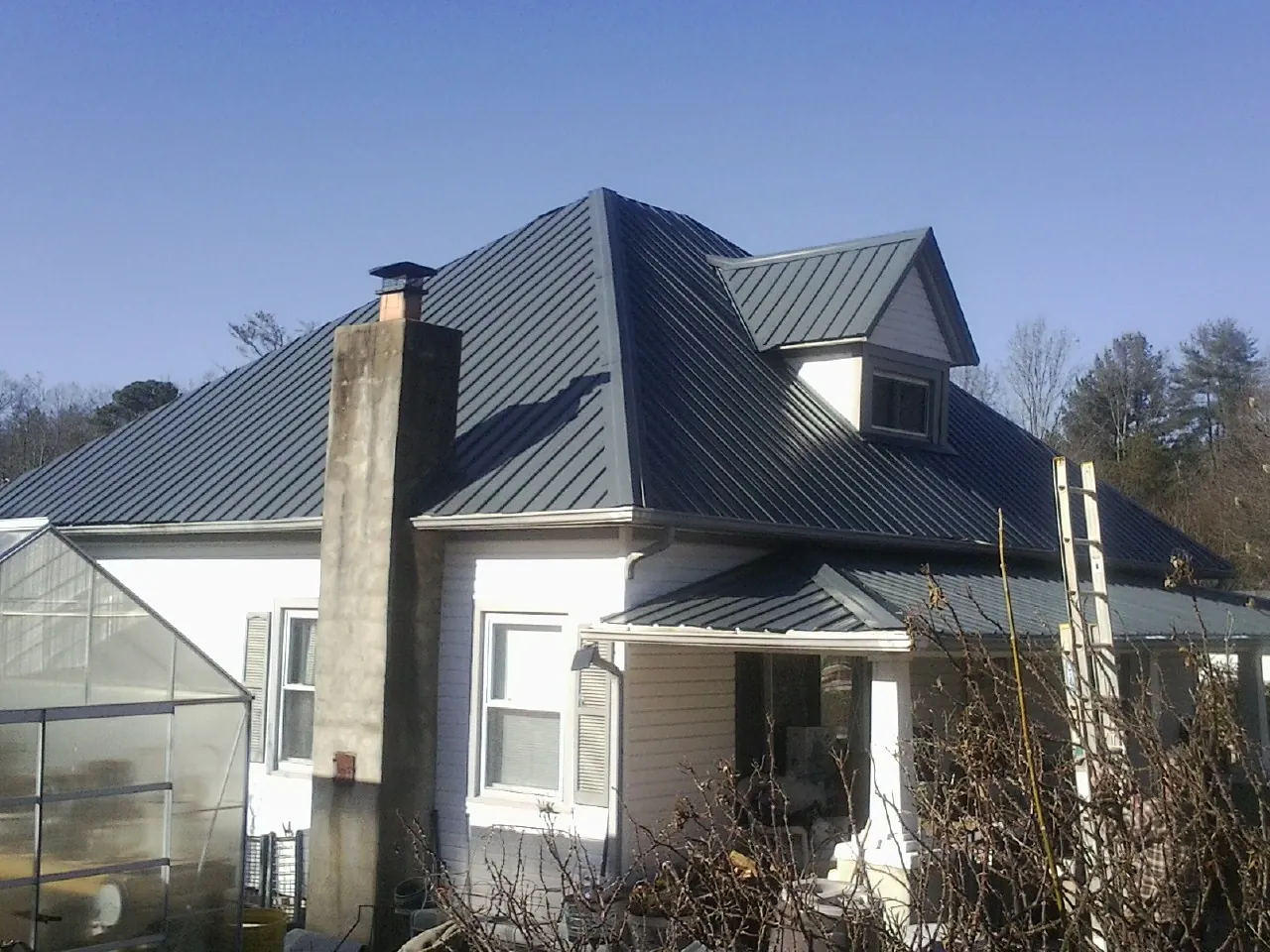 Dark blue standing seam metal roof on a white farmhouse with dormer — Slate & Tile Roof Repair by Roofing Brothers in Drewryville