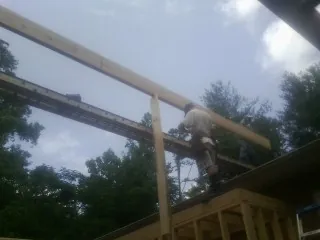 Carpenter setting a ridge beam over a new addition frame — Ice Dam Removal by Roofing Brothers in Drewryville