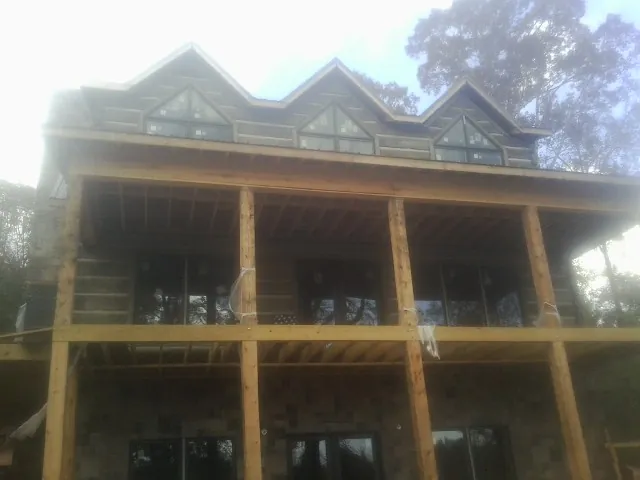 Dormers and porch framing on a large log home under construction — Roof Coating work by our crew in Drewryville