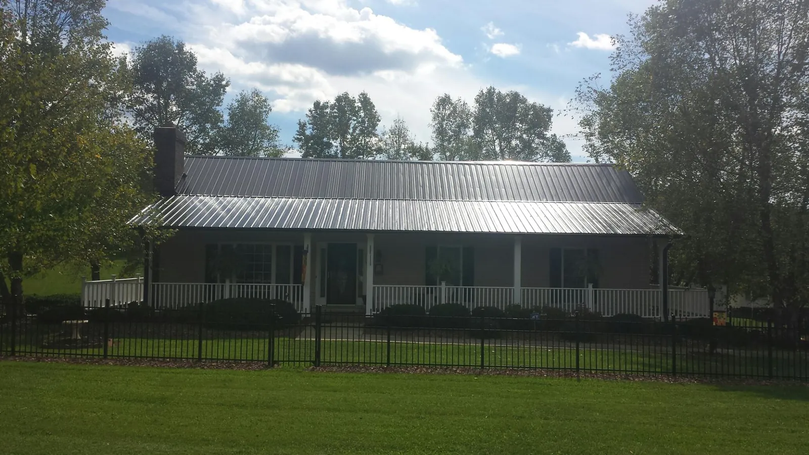 Gray metal roof on a brick ranch with a full width front porch — Gutter Guard Installation work by our crew in Drewryville