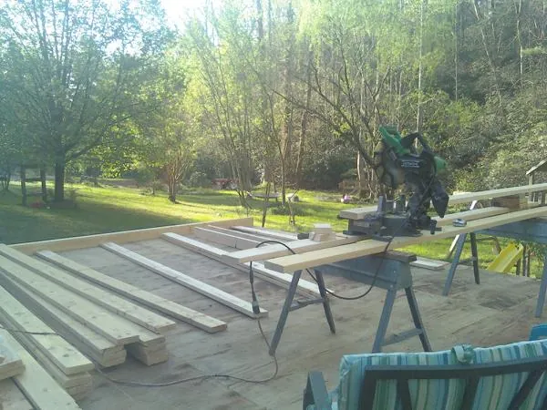 Miter saw and framing lumber on a deck under construction in Drewryville