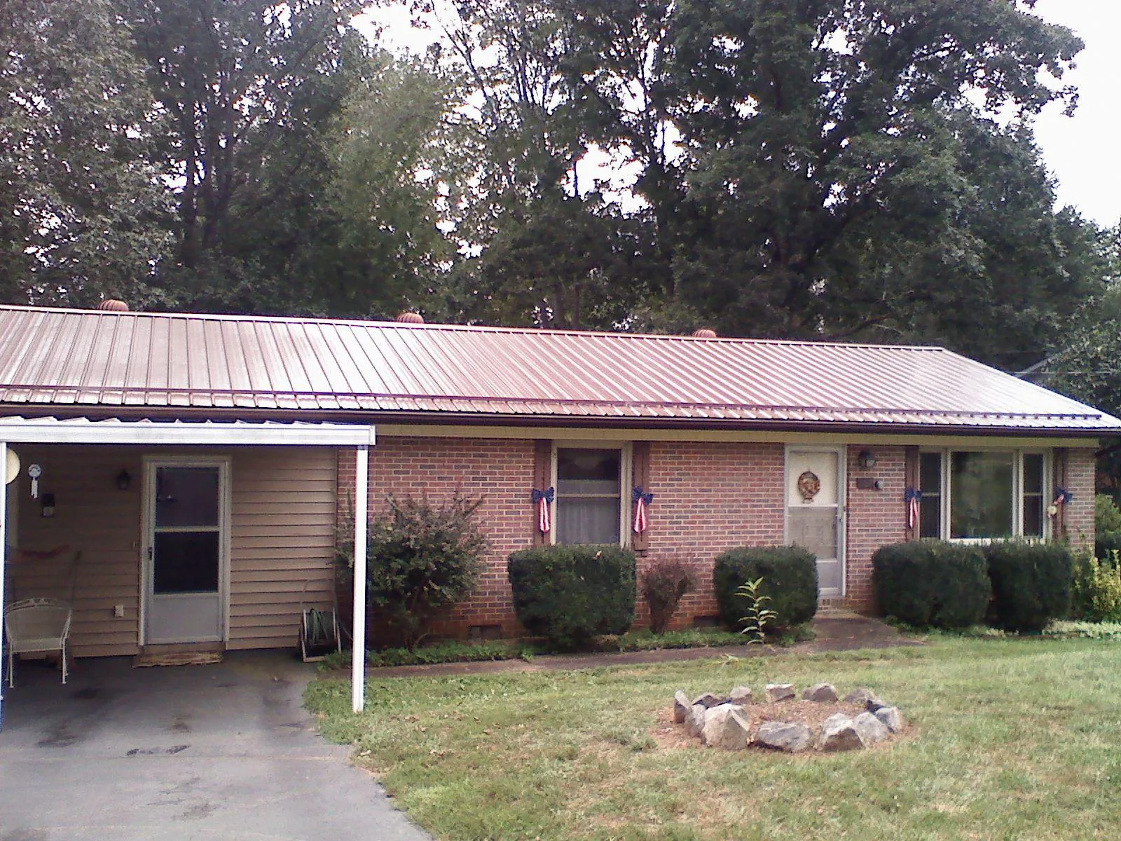Bronze metal roof and carport on a brick ranch home — Roof Repair work by our crew in Drewryville