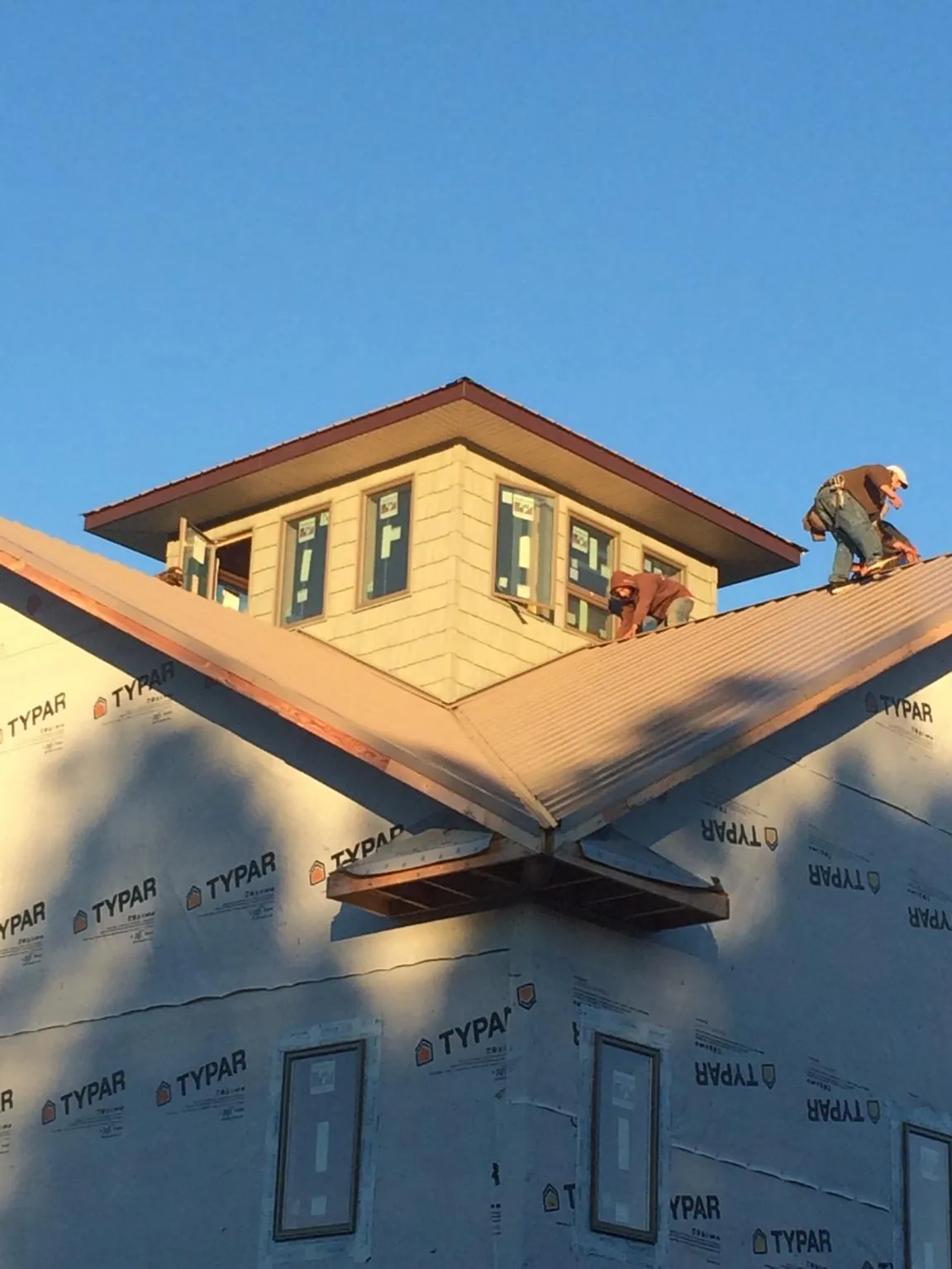 Roofers working around a rooftop cupola on a new metal roof at sunset — Roof Waterproofing in Drewryville by Roofing Brothers